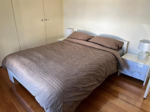 Clouston Cottage في Heathcote: سرير في غرفة نوم مع مواقف ليلتين ومصباحين