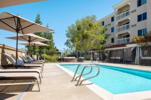 una piscina con sillas y sombrillas junto a un edificio en Courtyard Novato Marin/Sonoma, en Novato