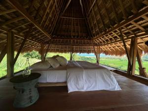 a bed in a straw hut with a table in front of it at Sumba Farm House in Sumba