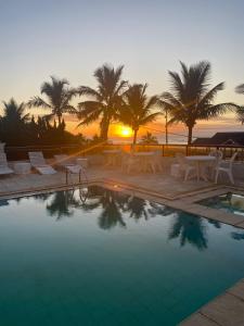 een zwembad met stoelen en een zonsondergang op de achtergrond bij Ancora Peruibe Hotel in Peruíbe