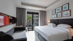 カタビーチにあるSugar Marina Hotel-SURF-Kata Beach - SHA Plusのベッドルーム(大きな白いベッド1台、ソファ付)