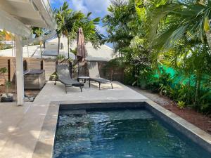 a swimming pool in a backyard with two chairs and an umbrella at Villa La Tapatia in Le Diamant
