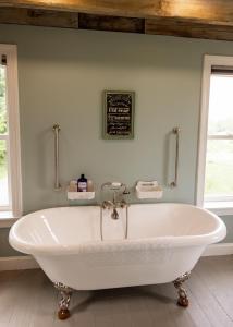 a white bath tub in a bathroom with two windows at Valley View Cabin in Morris