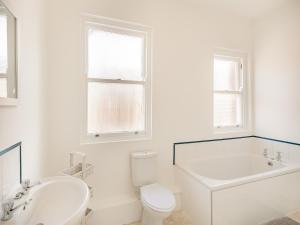 a white bathroom with a tub and a toilet and a sink at Clifton Apartment - Uk42845 in Lytham St Annes