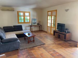 a living room with a couch and a tv at Villa La Tapatia in Le Diamant