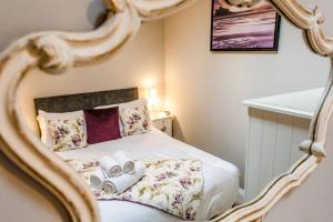 a bedroom with a bed with a gold framed mirror at Nurse's Cottage in Alnwick