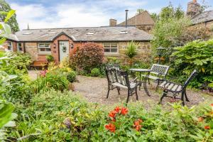 a garden with a table and chairs in front of a house at Nurse's Cottage in Alnwick