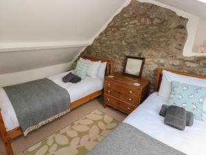 a bedroom with two beds and a stone wall at Briar Cottage in Neyland