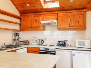 a kitchen with wooden cabinets and a counter top at Dunstanburgh View in Embleton