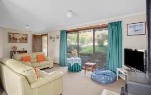 a living room with a couch and a tv at Comfortable Elevated Holiday Home in Encounter Bay