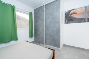 1 dormitorio con 1 cama y cortina verde en Fare Taharaa 1BR in Arue, en Arue