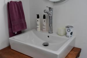 lavabo blanco en el baño con toalla púrpura en Casa Entre Ulmos y Lengas en Puerto Natales