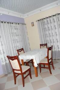 a dining room with a table and chairs and curtains at Maison Verte a Cococodji in Cococodji