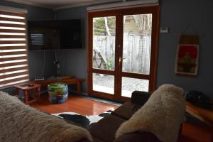 uma sala de estar com um sofá e uma porta de vidro deslizante em Casa Entre Ulmos y Lengas em Puerto Natales