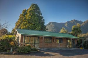 a small building with mountains in the background at Rainforest Motel in Fox Glacier