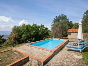 an outdoor swimming pool with an umbrella and two chairs at Farmhouse in Castelfranco Piandisc with Garden in Castelfranco di Sopra