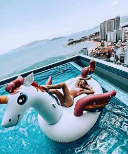 two women laying on a unicorn raft in a swimming pool at Scenia Bay Residence Nha Trang in Nha Trang