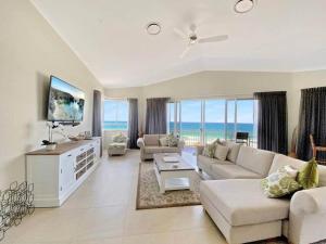 a living room with a couch and a tv and the ocean at Aquarius Resort in Alexandra Headland
