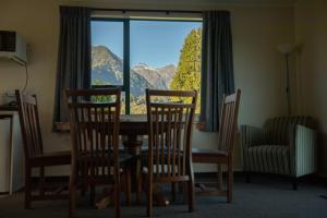 una sala da pranzo con tavolo, sedie e finestra di Rainforest Motel a Fox Glacier