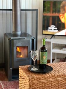 una botella de vino y una copa en una mesa con chimenea en Casa Toscana junto al río, en El Bolsico