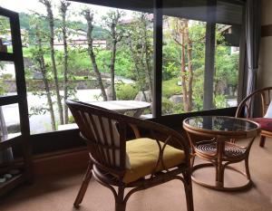 a room with two chairs and a table and a window at Pension Amagiji in Izu