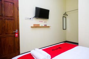 Cette chambre comprend un lit avec une couverture rouge et une télévision. dans l'établissement RedDoorz near Tirtonadi Park Solo, à Kadiporo