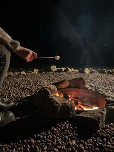 una persona cocinando sobre un fuego con una olla y un palo en Casa Toscana junto al río, en El Bolsico