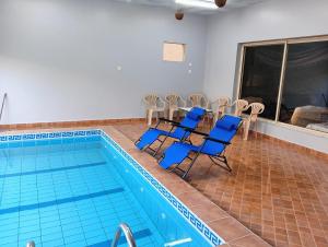 a pool with blue chairs and a table and a swimming pool at Villa Marmara in Medina