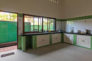 eine Küche mit grünen und weißen Arbeitsflächen und Fenstern in der Unterkunft HOUSE OF HAPPINESS in Thongsala