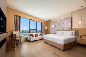 ein Schlafzimmer mit einem großen weißen Bett und einem Sofa in der Unterkunft Wyndham Grand Plaza Royale Yuzhou Xiamen - Wuyuan Bay in Xiamen