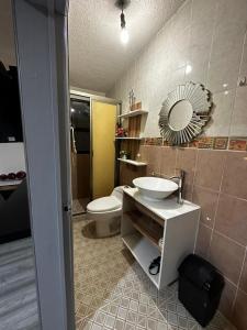 een badkamer met een wastafel, een toilet en een spiegel bij Casa Marín in Oaxaca City
