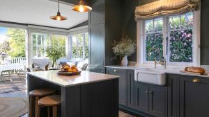 a kitchen with blue cabinets and a sink and windows at Werona Cottage - enchanting home in Burrawang
