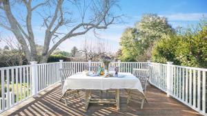 a table on a deck with a white fence at Werona Cottage - enchanting home in Burrawang