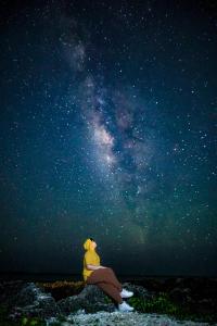 a person sitting on a rock looking up at the universe at 白海民宿 Lunar Mare Inn in Xiaoliuqiu