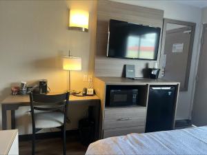 Habitación de hotel con escritorio, TV y cama en Red Roof Inn Bourbonnais en Bourbonnais