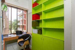 雪梨的住宿－Tranquil 1 Bedroom Apartment - Rushcutters Bay Self-Catering，办公室设有绿色的书架、桌子和椅子