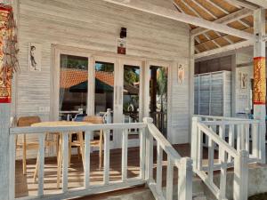 un porche de una casa con mesa y sillas en Blue Sky Villa Ceningan en Lembongan