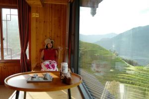 een vrouw in een kamer met een groot raam bij Longji One Art Hotel in Longsheng