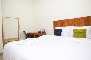 een slaapkamer met een groot bed met witte lakens en kussens bij Urbanview Syariah Kadarman Home Laweyan by RedDoorz in Grogol