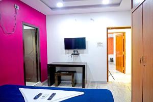 a room with a bed and a desk with a tv at Sea side guest house vizag in Visakhapatnam