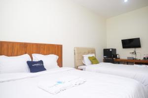 een hotelkamer met 2 bedden en een televisie bij Urbanview Syariah Kadarman Home Laweyan by RedDoorz in Grogol