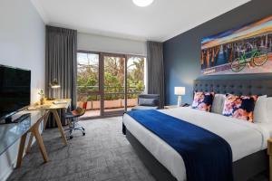 墨尔本Kimberley Gardens Hotel, Serviced Apartments and Serviced Villas的配有床、书桌和电视的酒店房间