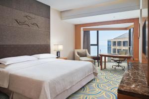Sheraton Yantai Golden Beach Resort في يانتاى: غرفة في الفندق مع سرير ومكتب