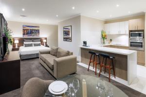 a living room with a couch and a kitchen with a bed at Kimberley Gardens Hotel, Serviced Apartments and Serviced Villas in Melbourne
