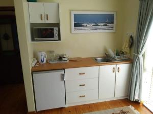a kitchen with white cabinets and a sink and a microwave at OppiKrom Rivertide 36 in Kromriviermond