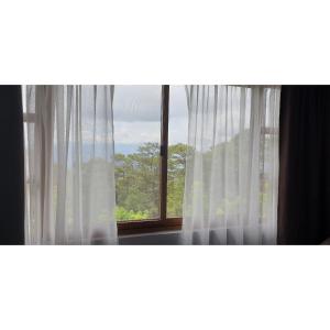 a window with white curtains in a room at The Forest Lodge at Camp John Hay privately owned unit with parking 545 in Baguio