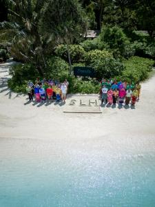 a group of people standing next to a sign on the beach at Zeavola Resort in Phi Phi Don