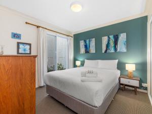 een slaapkamer met een groot wit bed en een raam bij Nautica on Marine Parade by Kingscliff Accommodation in Kingscliff