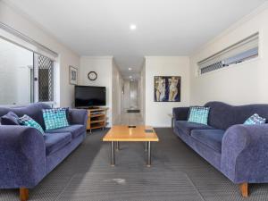 een woonkamer met twee blauwe banken en een salontafel bij Nautica on Marine Parade by Kingscliff Accommodation in Kingscliff