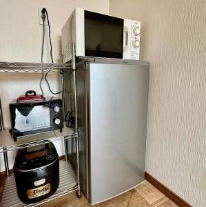 a microwave sitting on top of a refrigerator at KOTORI HOUSE in Kyoto